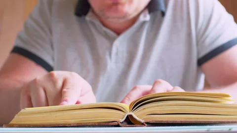 Close-up of cinematic footage reading an old book in a modern home. Stock Footage 336200545