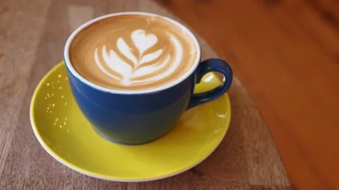 Close up cinematic footage of a steaming cup of coffee with latte art on a .. Vídeos de archivo 332192607
