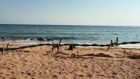 Close Up cinematic motion along Barbed Wire on Sandy Beach Shore with Calm Sea a Vídeo Stock 333247050