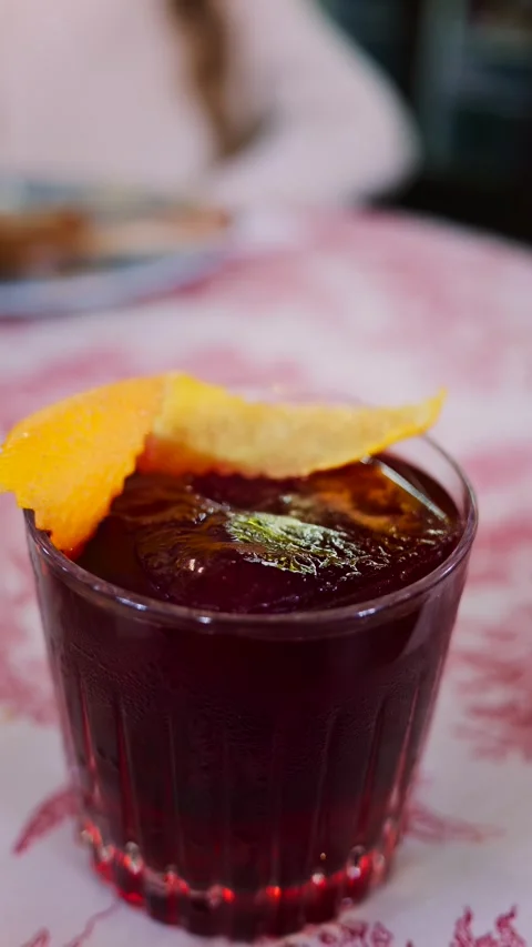 Close-up cinematic shot of dark red cocktail in glass with orange peel garn.. Stock Footage 339412559