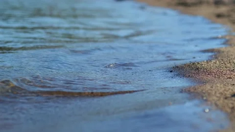 Close-up cinematic shot small waves on the sandy beach. Видео 255548506