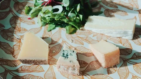 A close up cinematic view of cutting cheese with a knife and fork on a plat.. Vídeos de archivo 339203517