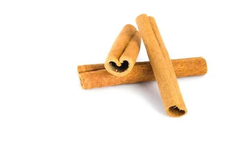 Close-up of cinnamon bark segments on a white surface, highlighting their c.. Stock Photos