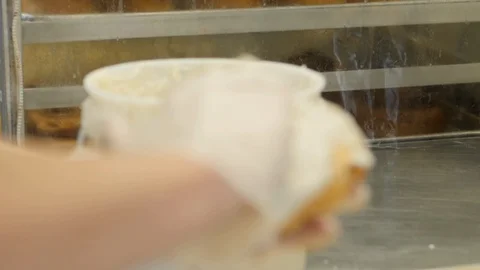Close up of cinnamon roll getting iced by gloved hand Video stock 93380793
