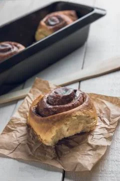 Close-up of a cinnamon roll over a white rustic wooden table Stock Photos