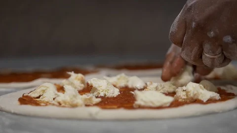 Close-up of a circle of pizza and hands of a chef who is laying out mozzarella Stock Footage 104866041