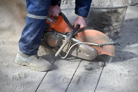 Close-up of a circular saw in the hands of a worker cutting asphalt. Stock Photos
