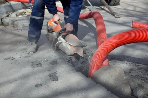 Close-up of a circular saw in the hands of a worker cutting asphalt. Stock Photos