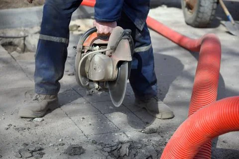 Close-up of a circular saw in the hands of a worker cutting asphalt. Stock Photos