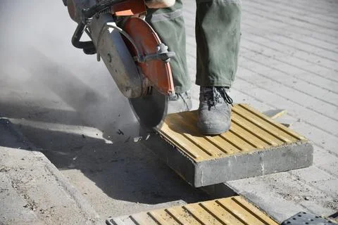 Close-up of a circular saw as a worker cuts a road curb. Stock Photos