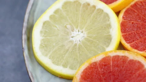 Close Up Of Citrus Fruit Spinning on Plate. Pink Red Grapefruit. Lemons. Vegan. Video stock 153609846