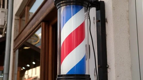 Close-up of a classic barber pole mounted outside a traditional barbershop Vídeo Stock 346690196