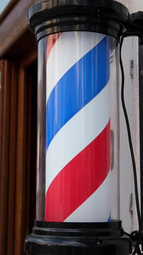 Close-up of a classic barber pole mounted outside a traditional barbershop Video stock 346690220