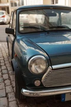 Close-up of a classic blue Mini Cooper parked on a cobblestone street in Al.. Stock Photos