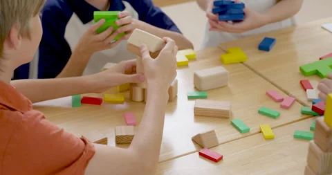 Close classroom view of children building with wooden blocks and colorful tiles Stock Footage 336066802