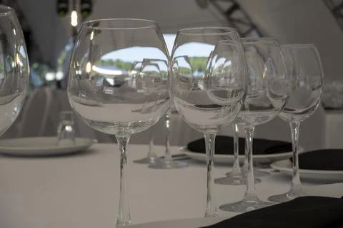 Close up clean empty wine glasses on white served dinner table in party tent Stock Photos