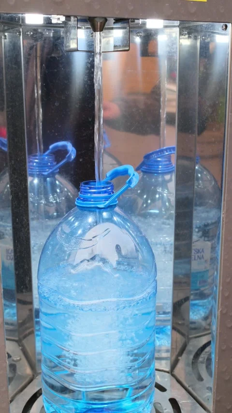 Close-up of clean water pouring into a blue gallon bottle at a modern urban w Stock Footage 334683744