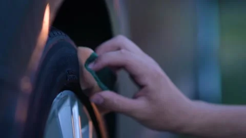 Close-up of cleaning a car wheel. A young man is using a sponge to blacken .. Stock Footage 278621163