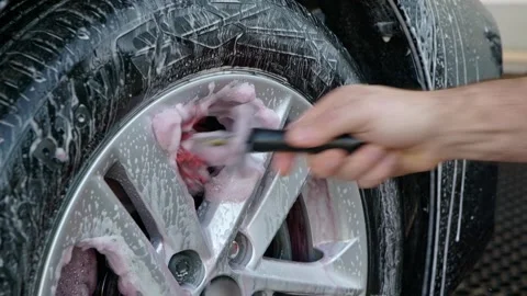 Close up cleaning silver alloy wheels with snow foam shampoo and iron removing Stock Footage 318437647