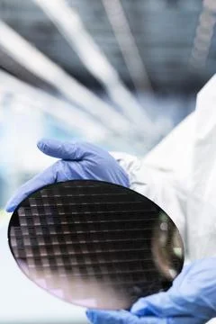 Close up of cleanroom engineer holding processed silicon wafer Stock Photos