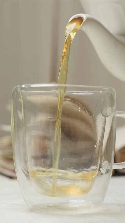 Close up of clear double walled mug being filled with brewed tea from white Stock Footage 347626735