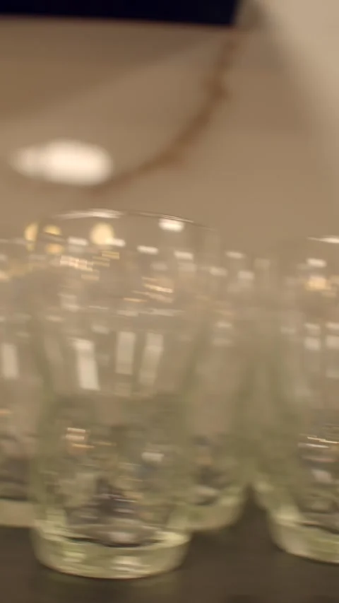 Close-up of clear drinking glass on dark store shelf with blurred colorful 库存影片 336533898