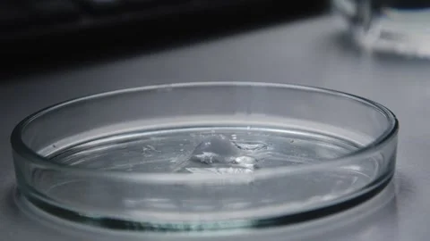 Close-up A clear liquid dripping onto a dry white substance that begins to melt Stock Footage 260938800