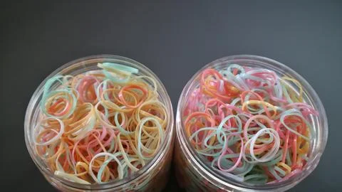 Close up Clear plastic jars filled with pastel rubber bands Stock Photos