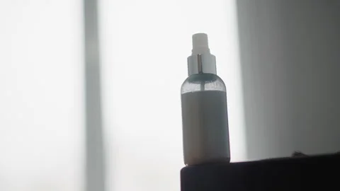 Close up clear plastic spray bottle with white liquid inside positioned against Vídeos de archivo 346730226