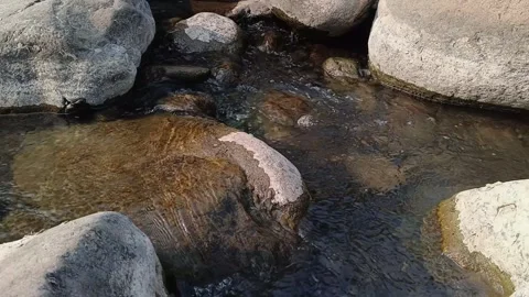 Close-up clear river water flows smoothly around large rocks in natural surr Stock Footage 344087969