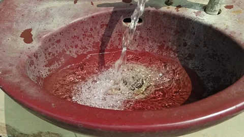 Close up of clear tap water flowing into a red basin creating bubbles 스톡 동영상 345339131