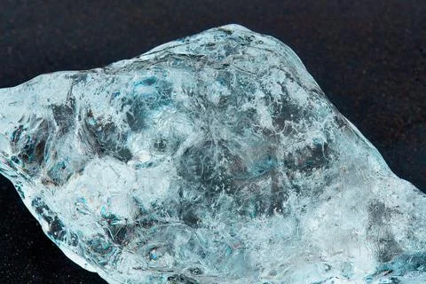 Close-up of a clear, textured ice chunk that looks like a diamond on a dark.. Stock Photos