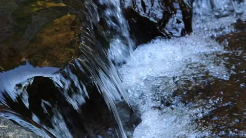 Close-up of clear water cascading over rocks in a natural forest stream. Stockbeeldmateriaal 346868836