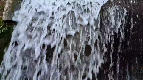 Close up of clear water flowing down a dark surface, natural waterfall Stock Footage 341681384