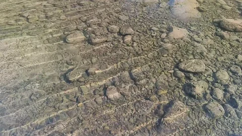 Close up of clear water flowing gently over river stones during the dry seas Stock Footage 345569314