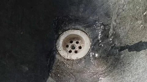 Close-up of clear water pouring into a stone basin drain hole Видео 341675615