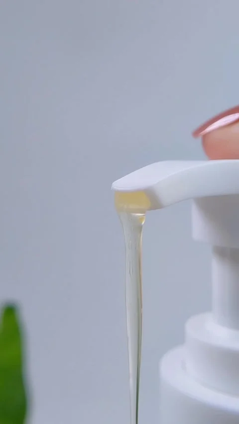 Close up of clear yellowish liquid coming out from pump bottle packaging. C.. Stock Footage 338171413