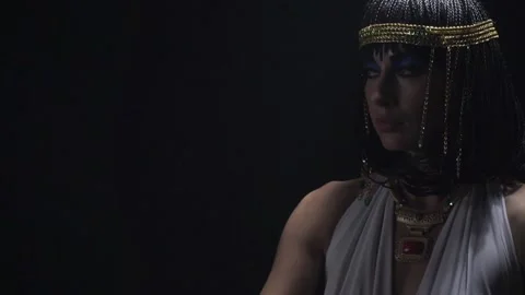 Close up of Cleopatra posing in dark room, wearing jewelry and blue makeup Stock Footage 138140136