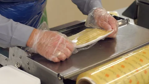 Close-up of the clerk slices the cheese in the store and put it in a packaging. Stock Footage 115336352