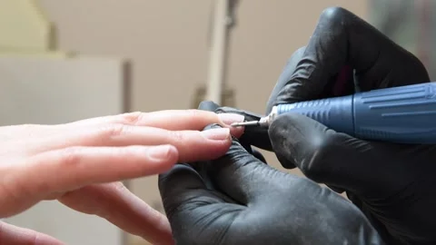 Close-up of clients hands where manicurist in black gloves treats her cuticles Stock Footage 284557716