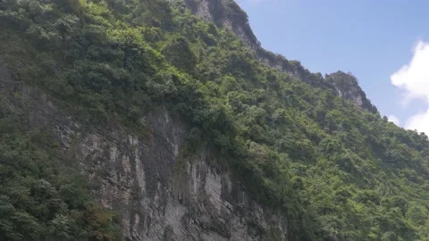 Close-up of a cliff bordered by a tropical forest filmed from a boat, in China Stock Footage 232180652