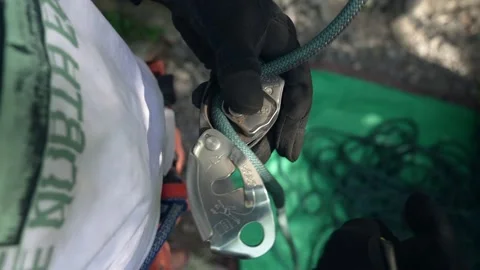 Close up of climber putting rope through belay device to rock climb safely gear Video stock 167048309