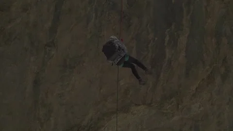 Close Up of Climber Slowly Descending Rope Along Dark Rock Wall Vidéo 345632419