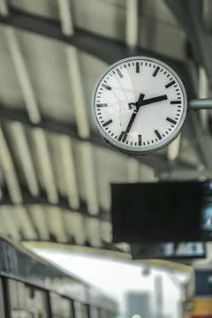 Close up of clock at sky train terminal screen in the back and train is coming Stock Photos