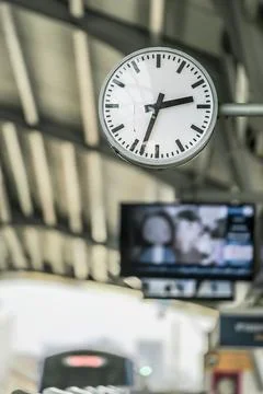 Close up of clock at sky train terminal screen in the back and train is coming Stock Photos