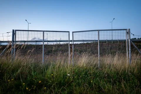 Close up of a closed metal mesh gate against the sky during the evening Stockfoto's