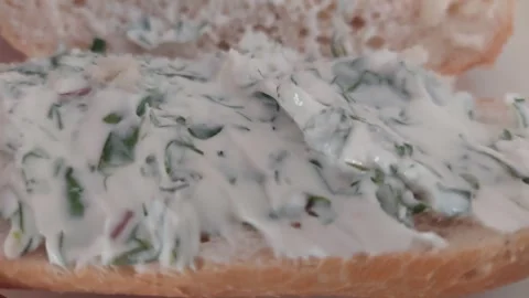 Close-up of closing a sandwich bun spread with white herb cream cheese sauce Vídeo Stock 337052660