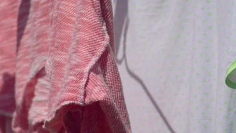 Close up Clothes drying in the little wind on a clothesline outside in the sun Stock Footage 82395151