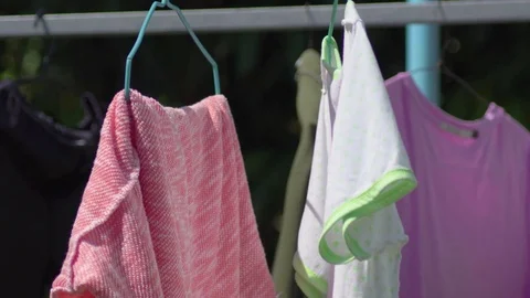 Close up Clothes drying in the little wind on a clothesline outside in the sun Vídeos de archivo 82395166