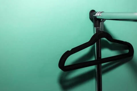 Close-up of clothes rack with black empty hangers on background of aqua menthe. Stock Photos